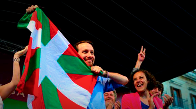 Pablo Iglesias con una bandera vasca en un acto de Podemos.