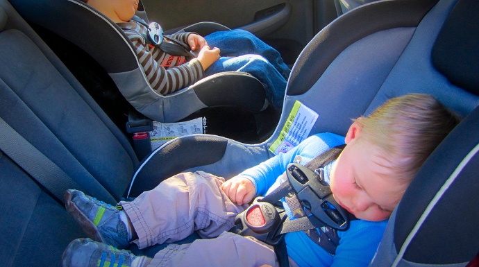 Dos pequeños en sus sillas de sujeción infantil en el coche.