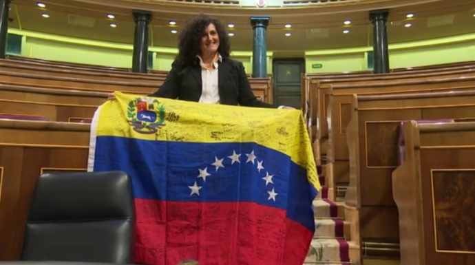 Una opositora venezolana al colocar este jueves una bandera de su país en el escaño de Pablo Iglesias.