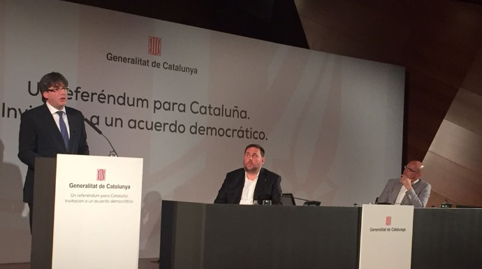 Puigdemont, durante su conferencia. Sentados, Junqueras y Romeva.