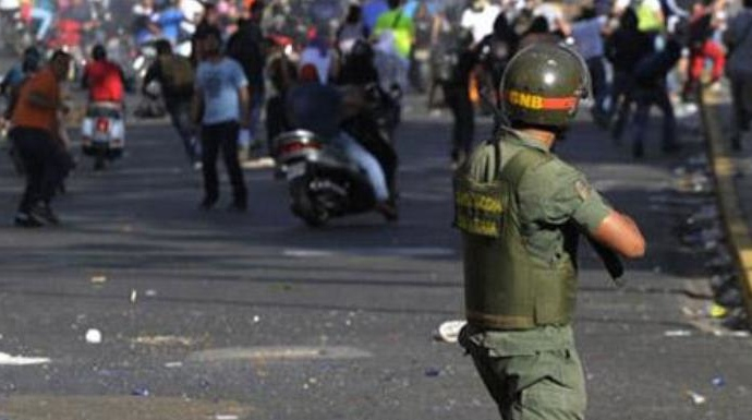 Un policía dispara a los manifestantes en una protesta contra Maduro.