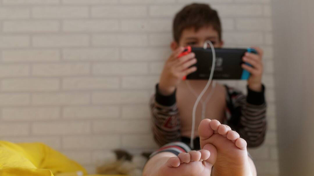 Un niño jugando a la videoconsola en su habitación.