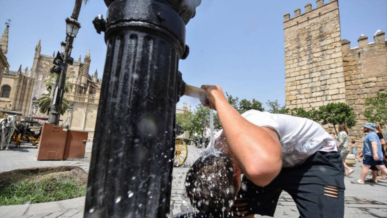 Un joven se refresca en una fuente en pleno centro de Sevilla.