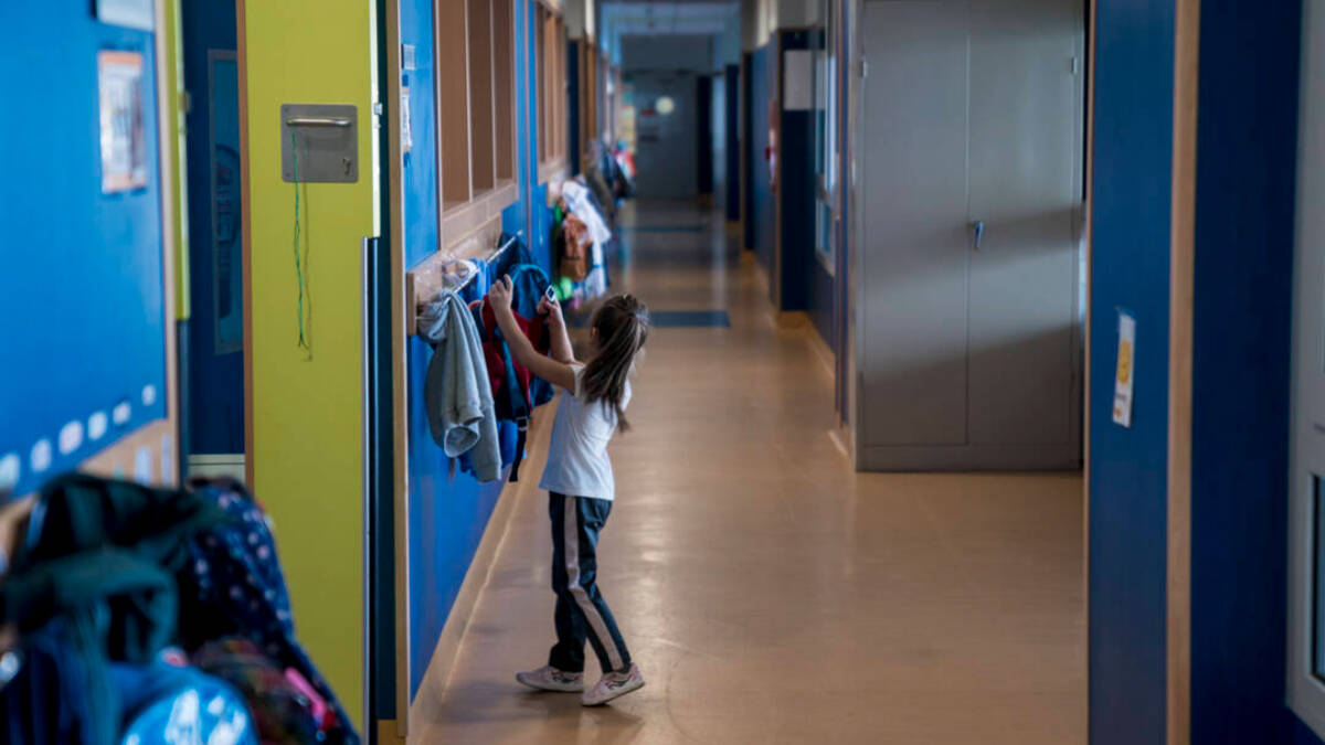 Una alumna cuelga una chaqueta en un pasillo del colegio