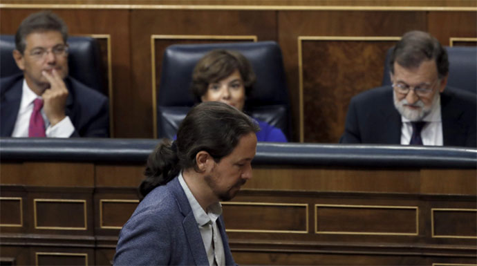 Iglesias pasa por delante del escaño de Rajoy durante el debate.