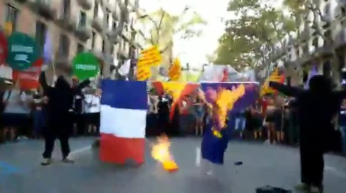 Encapuchados de la CUP (Arrán) quemando este lunes en la Diada la bandera de Francia, España y la UE.