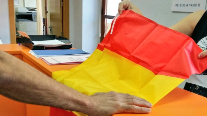 Un vecino de Archena (Murcia) recoge una bandera de España en el Ayuntamiento.