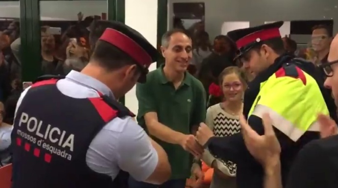 Dos mossos reciben una rosa en un colegio electoral que debían clausurar.