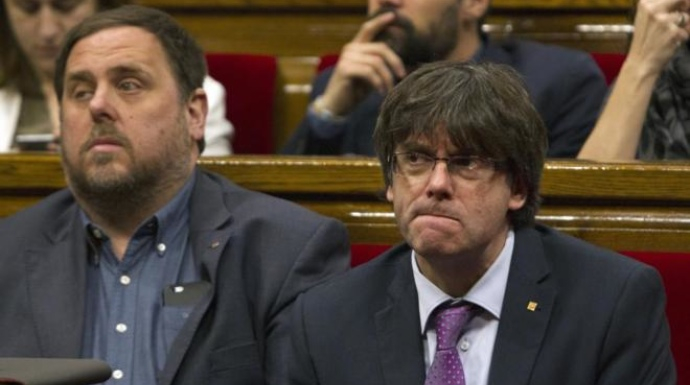 Puigdemont y Junqueras, en el Parlament, con gesto serio.