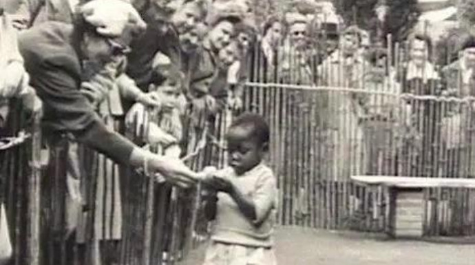 Visitantes intentando acariciar a una niña negra, en un zoo humano de Bélgica en 1958