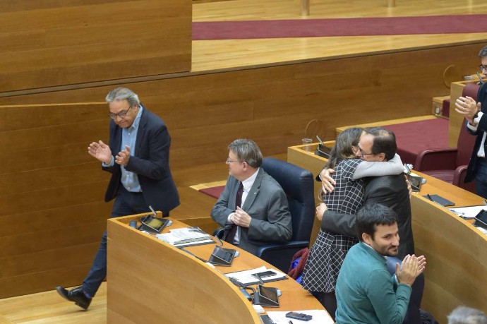El portavoz del PSOE, Mata, aplaude ante la mirada del presidente y el abrazo de Oltra y el conseller de Hacienda