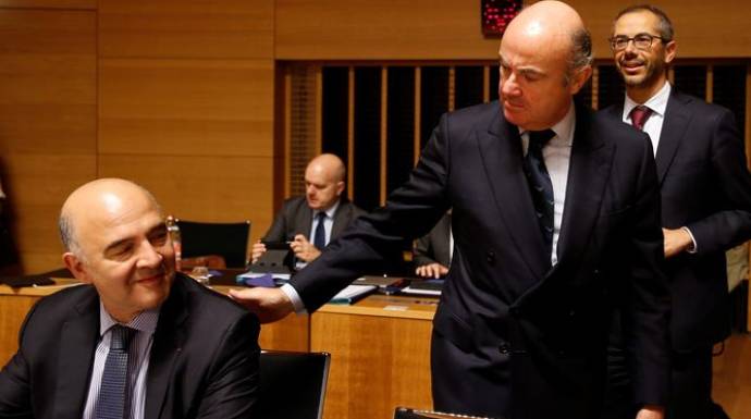 Luis de Guindos saluda al comisario europeo de Economía, Pierre Moscovici, en una reunión del Eurogrupo.