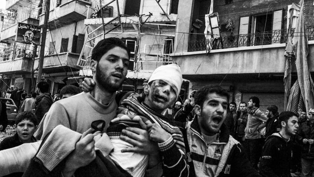 Un hombre carga a un niño herido tras un bombardeo de la aviación siria (Mauricio Morales-EP)