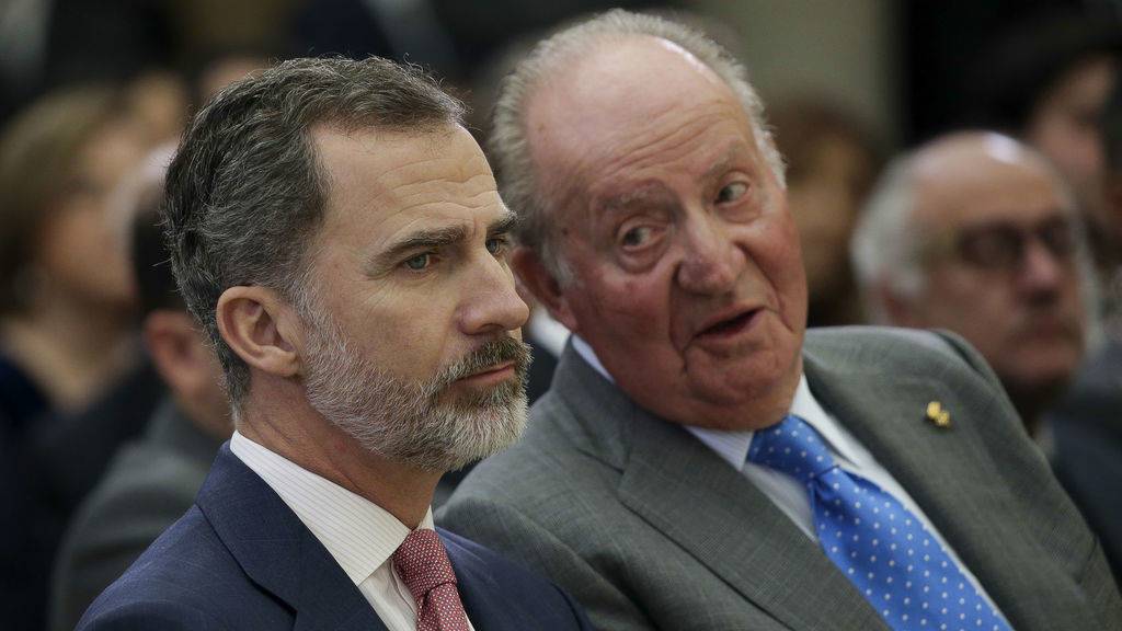 El Rey Felipe, con gesto visiblemente serio, escucha a Don Juan Carlos en un acto juntos.