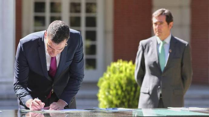 Sánchez, firmando el acuerdo con los agentes sociales ante la atenta mirada del líder de la CEOE.