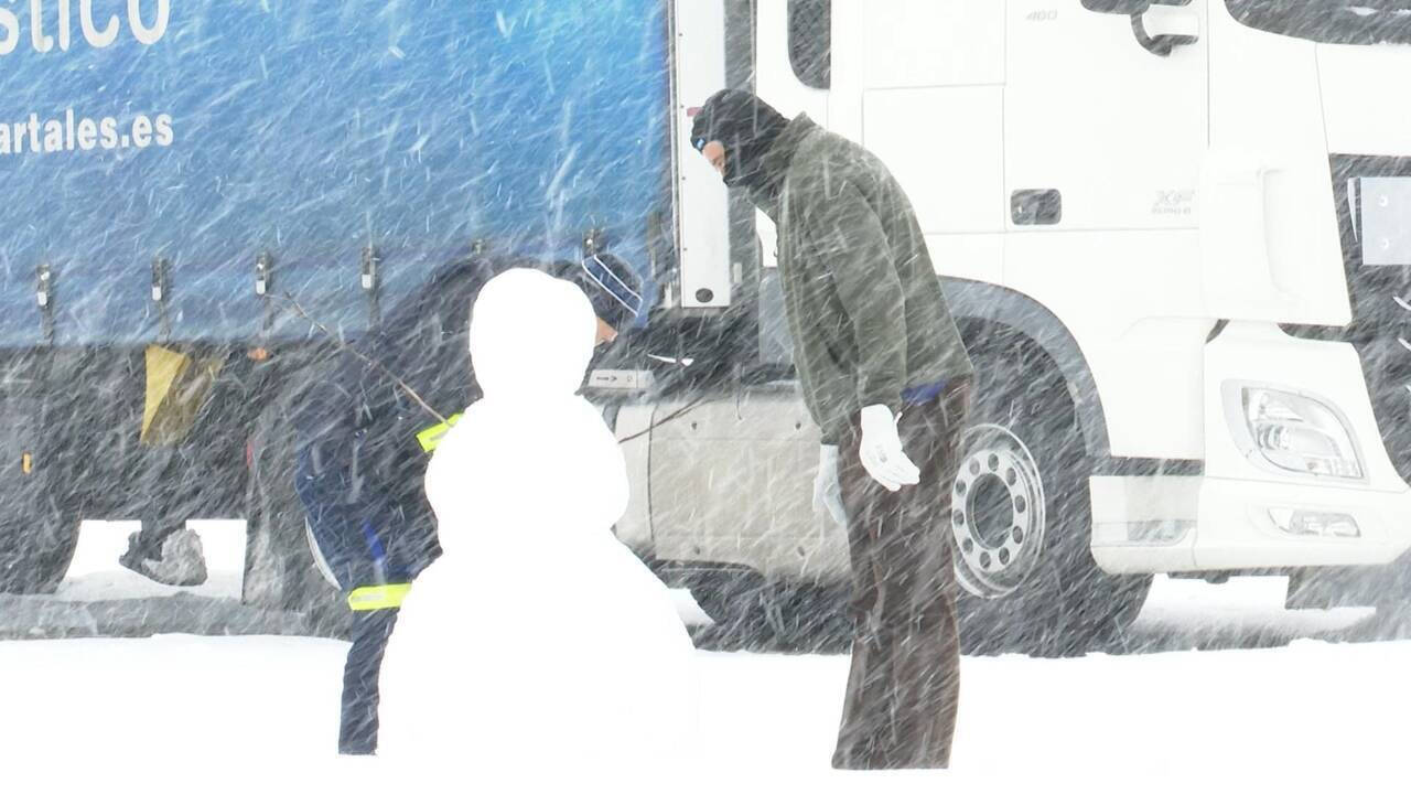 Un camionero atrapado por el temporal contempla un  muñeco de nieve.