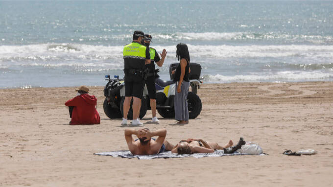 Dos policías municipales hablan con una mujer en una playa de Valencia, a 26 de mayo de 2021, en Valencia, Comunidad Valenciana (España)