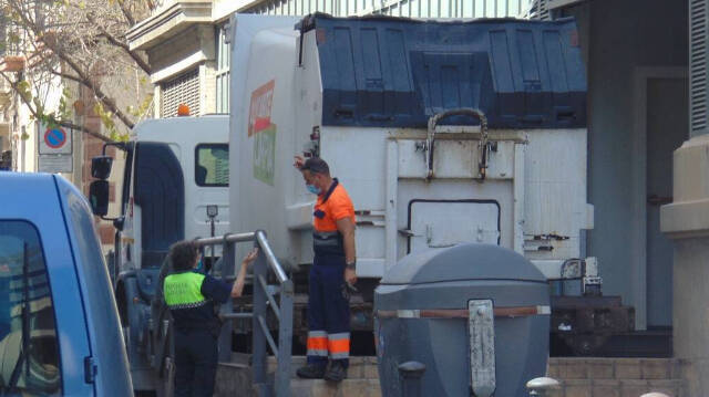 Un Policía Local dando indicaciones a un trabajador de recogida de resíduos