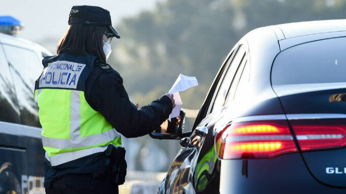Un agente de policía le pide la documentación a un conductor en un control