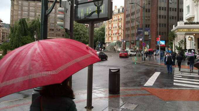 Una persona refugiada bajo un paraguas de la lluvia
