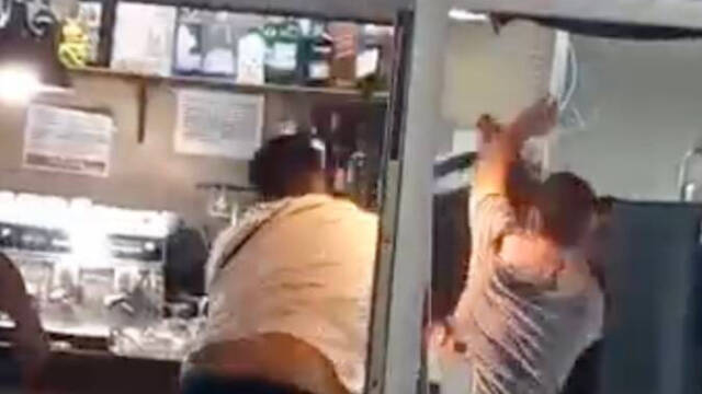 Momento en el que un hombre lanza una silla contra otras personas dentro del bar durante la pelea