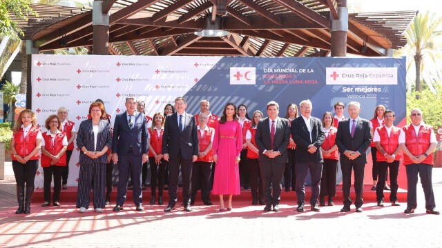 Su Majestad la Reina acompaña de los voluntarios de la Cruz Roja Española y de las autoridades asistentes al acto.