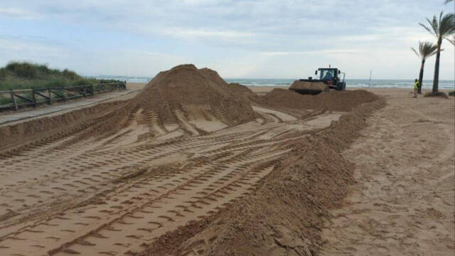 Costas extrae arena de la playa de Gandia en plena temporada turística