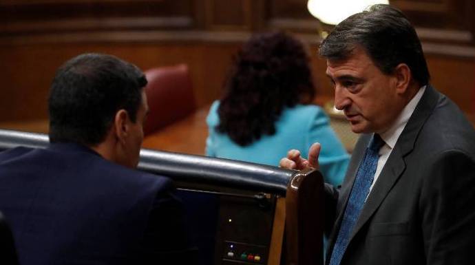 Aitor Esteban conversa con gesto serio con Sánchez en el escaño del presidente.