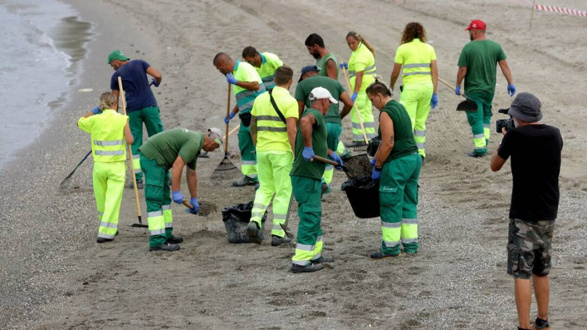 Operarios limpiando la playa de Poniente de La Línea tras la llegada de vertido procedente del OS35.


