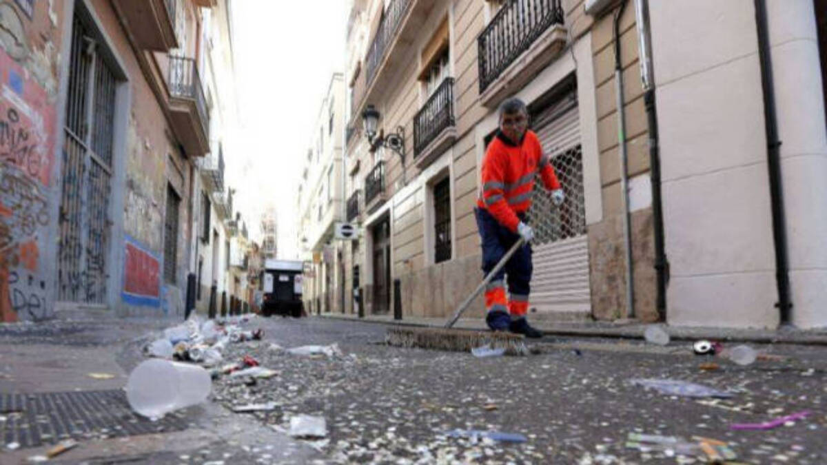 Una operario limpia una calle sucia de Valencia.