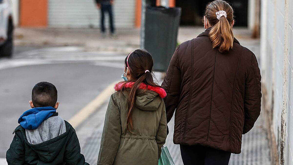 Un niño y una niña, acompañados de una mujer, caminan hacia el colegio público CEIP Antonio Machado.