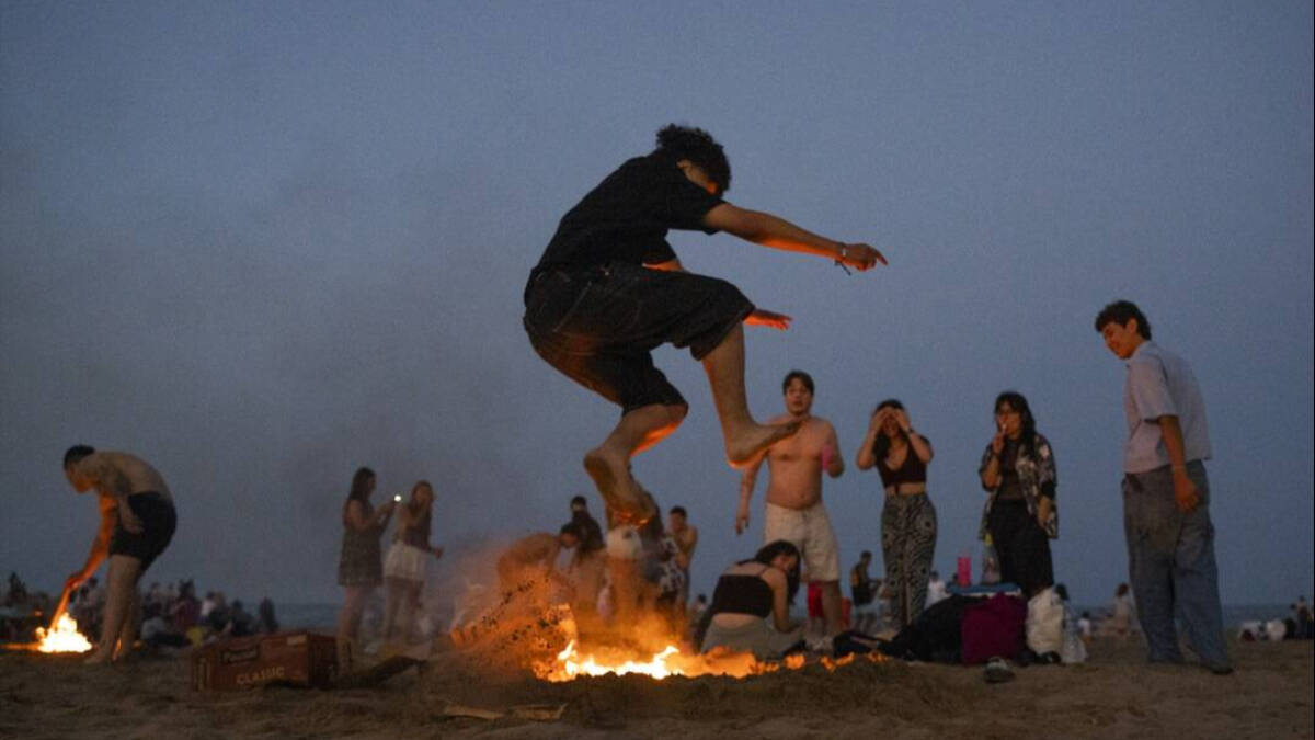 Una persona salta una hoguera durante la noche de San Juan, en la playa de la Malvarrosa / Jorge Gil.