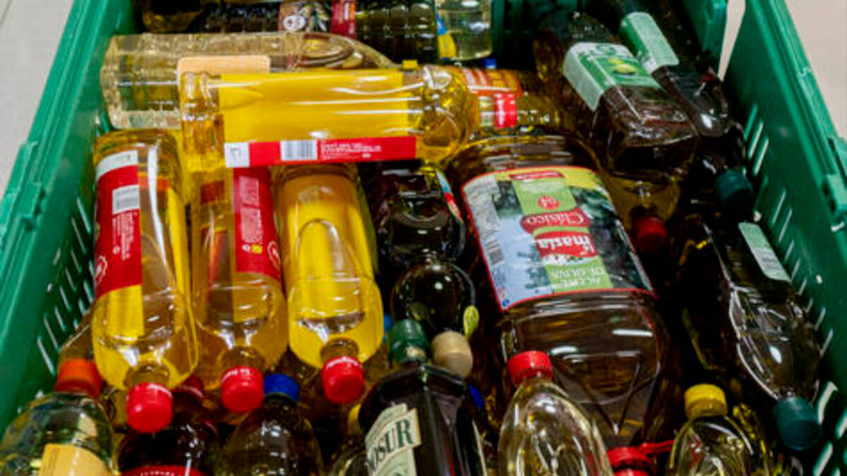 Imágen de diferentes botellas de aceite de oliva en el carrito de un supermercado