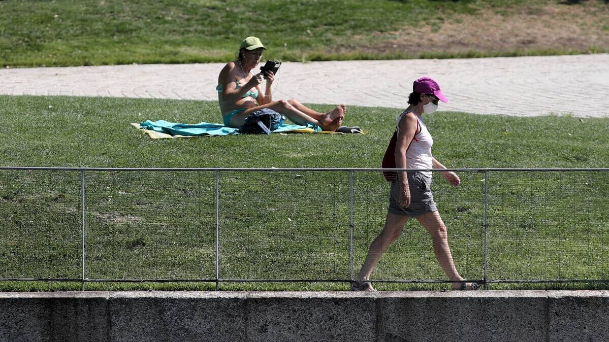Dos personas soportan las altas temperaturas en el Parque Madrid Río.