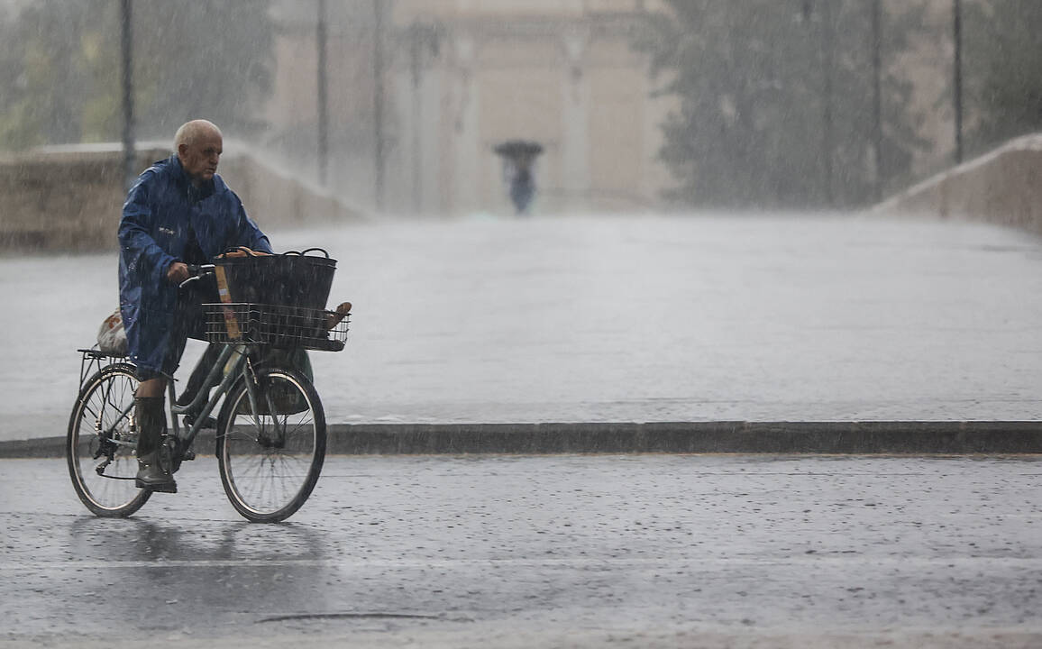 Imagen archivo persona bajo la lluvia de esta mañana en bicicleta por Valencia - EUROPA PRESS 
