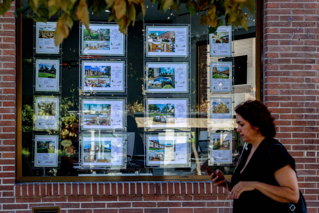Una mujer pasa frente a un comercio de compra-venta de pisos