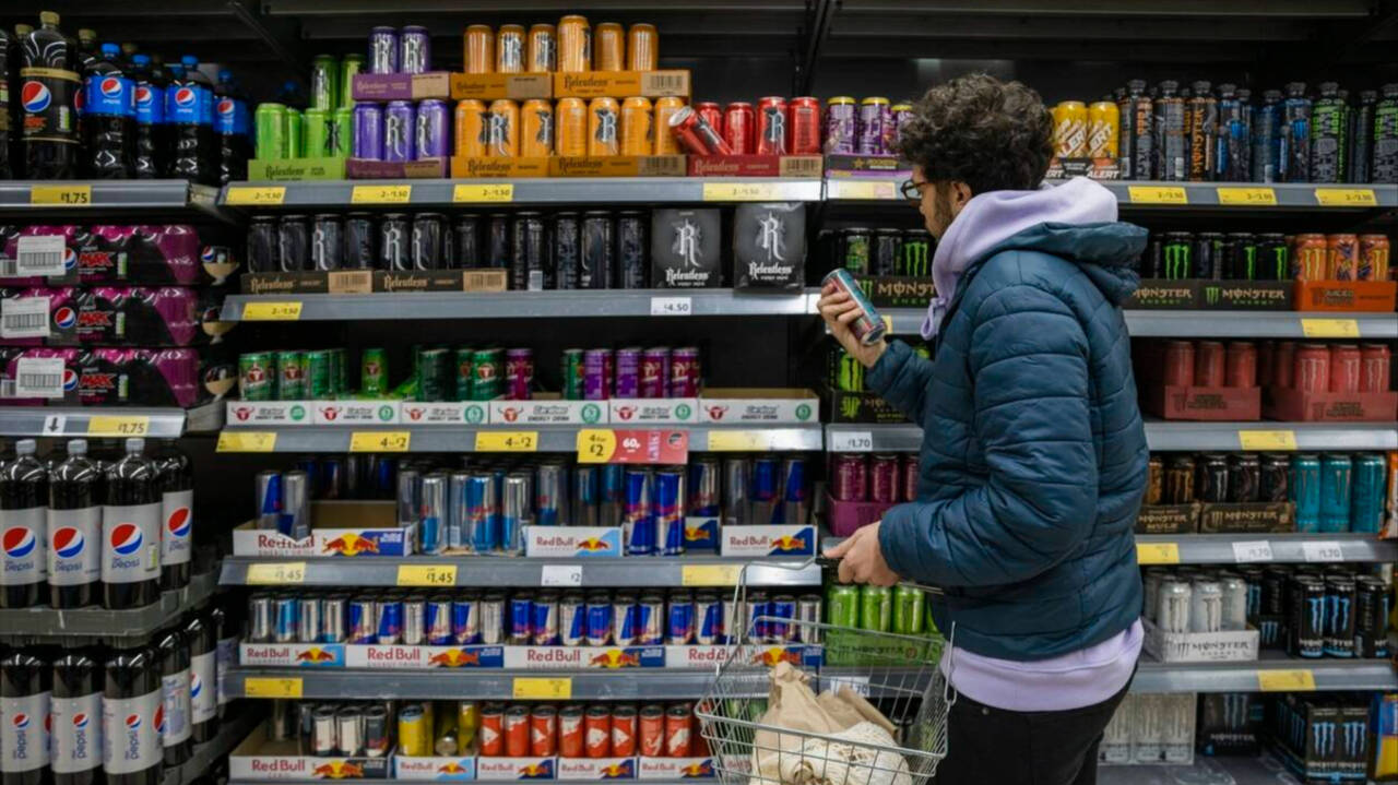 Un joven comprando bebidas energéticas en un establecimiento.