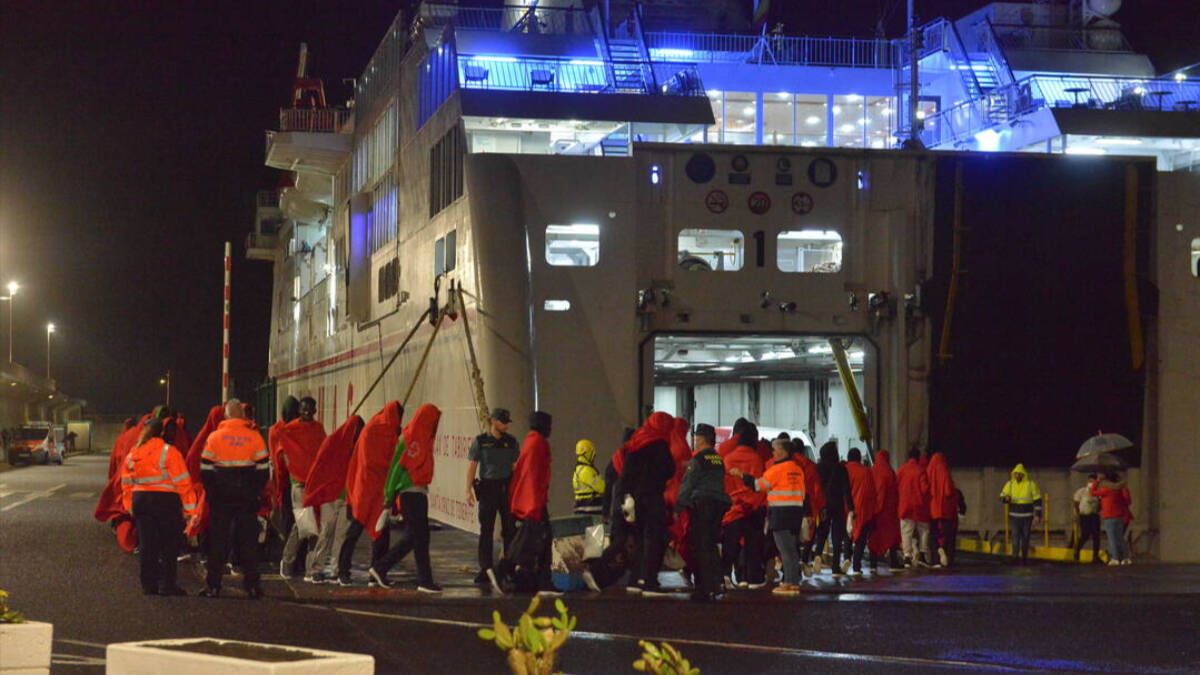 Decenas de inmigrantes hacen cola para entrar a un barco, en el muelle de La Restinga, en El Hierro.