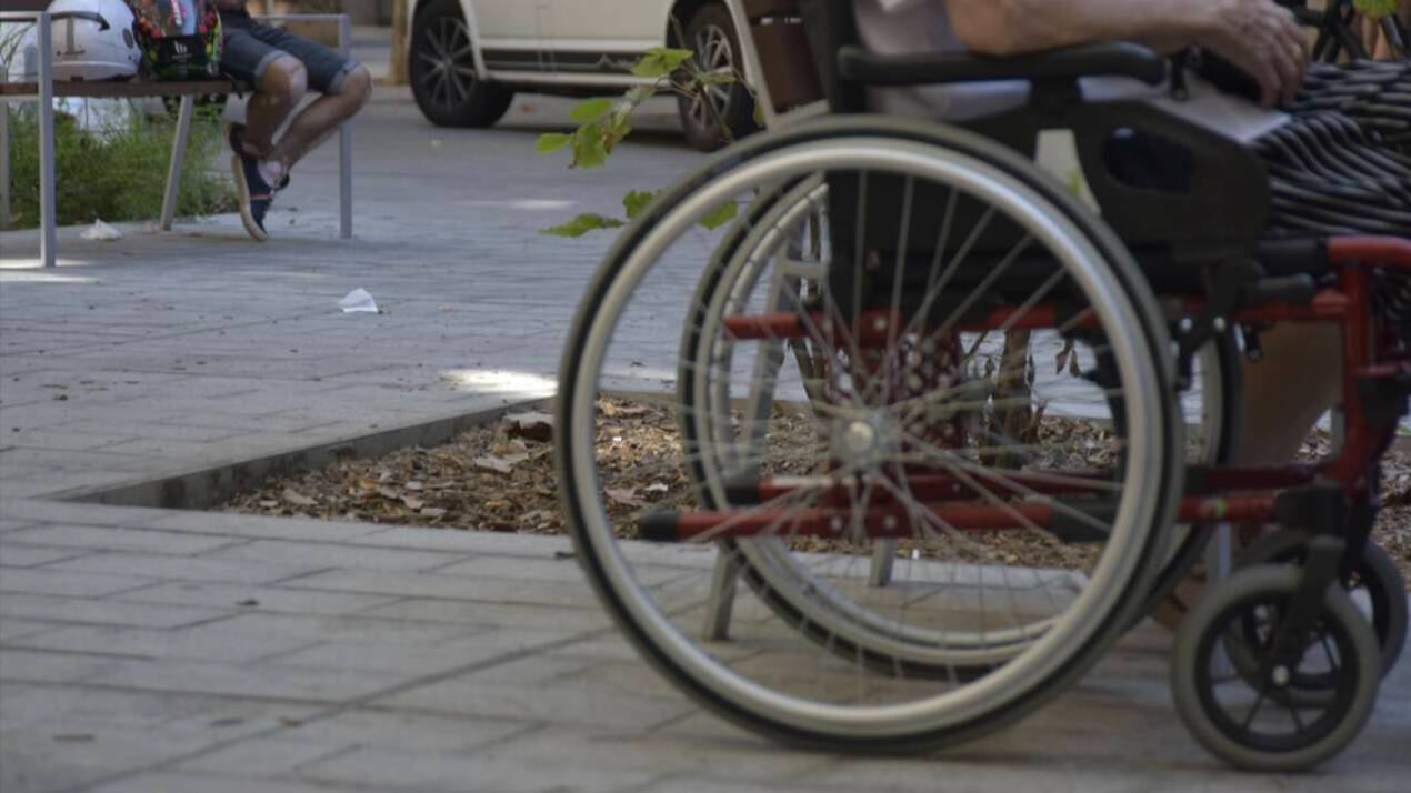 Una persona con dependencia circula por la calle en su silla de ruedas