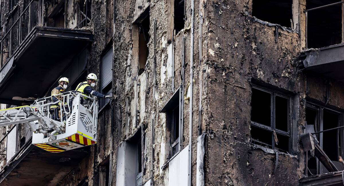 Bomberos en una grúa sanean la fachada quemada